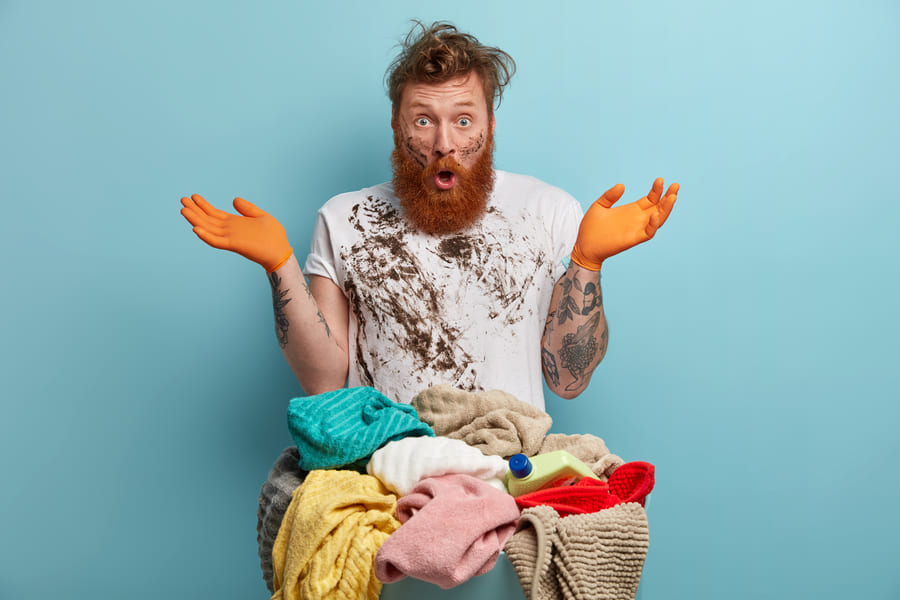 bearded-man-holds-laundry-basket-overwhelmed-by-household-chores